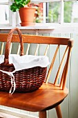 Handled basket lined with white cloth on 50s wooden bench in porch of Swedish wooden house