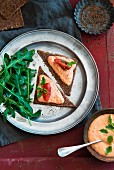Bread triangles topped with ricotta and tomato cream and rocket