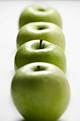 A row of four green apples