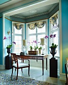 Violette Orchideen im Topf, neben Arbeitsplatz mit antikem Sekretär und Stuhl im Erker eines herrschaftlichen Salons, hellblau getönte Wände
