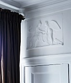 White, mythological low relief panel above traditional interior door with dark brown curtain to one side