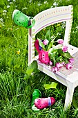 Tulpen und Gartenschuhe auf Kinderstuhl im hohen Gras