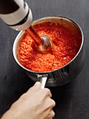 Tomato sauce being pureed with a hand mixer