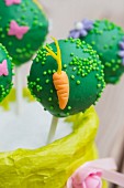 A green cake pop decorated with a carrot