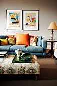 Blue sofa, colourful scatter cushions and tea set on tray on ottoman in living room