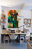 Zeitgenössische Malerei und künstlerische Objekte in Homeoffice mit einfacher Tischplatte auf Leiterbock und klassischem Schalenstuhl