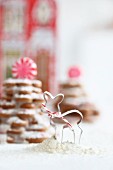 A cookie cutter in front of gingerbread biscuit trees decorated with icing sugar and peppermint bonbons