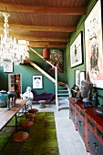Schlichte Holztischgarnitur gegenüber antikem, asiatischem Sideboard in eklektizistischem Wohnraum mit grünen Wänden und Holzbalkendecke