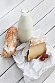 An arrangement featuring a bottle of milk, sheep's cheese and a baguette