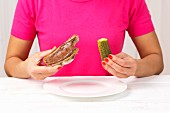 A woman eating a gherkin and a chocolate spread sandwich