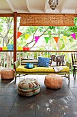Roofed terrace with colourful bunting and pouffes in summery garden atmosphere