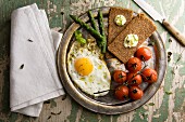 Fried egg with steamed tomatoes, asparagus and rye bread