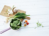 An arrangement of vegetables with garlic, spinach, spring onions and cherry tomatoes