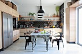 Metal, retro-style chairs around shabby dining chic table in designer kitchen
