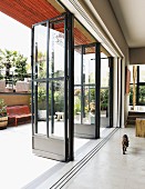 Cat walking through interior next to open lattice doors leading to summery terrace