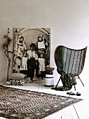Textiles with graphic patterns, mesh easy chair, painted wooden stool in front of life-sized black and white photo of African family