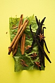 Cinnamon sticks, vanilla pods and star anise on a piece of green paper