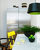 Marble table with yellow and black chairs; stainless steel, side-by-side fridge-freezer in background