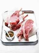 Raw pork chops with a spice mixture on a tray