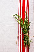 A bunch of rosemary on a red and white tea towel