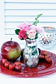 Vase in Bauernsilber-Optik mit Rosen und Dekoäpfel auf rotem Teller