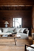 Pale, loose-covered sofa and rustic wooden coffee table in cabin living room