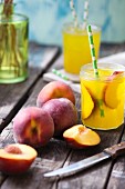 Peach juice and fresh peaches on a wooden table