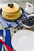 A table laid with a stack of pancakes and fresh blueberries