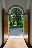 Offene, zweiflüglige Haustür mit Rundbogen-Oberlicht; Blick nach draußen auf Weg und Bäume