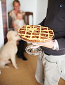 A man serving a pecan pie on a cake stand for Thanksgiving