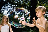 Zwei Kinder spielen mit Riesenseifenblase