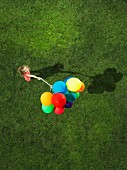 A girl holding a bunch of helium balloons