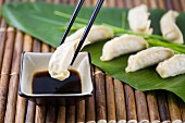 Gyoza being dipped into soy sauce (Japan)