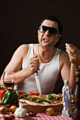 Typisch italienischer Mann sticht Messer in Schneidebrett neben Pizza
