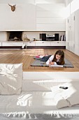 Kleines Mädchen beim Zeichnen auf Holzboden einer Empore im Wohnzimmer