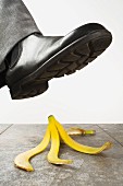 A foot wearing a boot about to tread on a banana peel