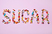 Das Wort SUGAR aus bunten Süßigkeiten gelegt