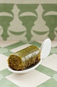 A green baklava roll on a canapé spoon