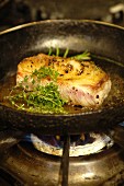 Pork fillet with peppercorns, thyme and rosemary in a pan