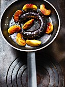 Fried blood sausage with apple wedges in a pan
