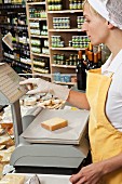 Verkäuferin wiegt ein Stück Käse im Lebensmittelladen