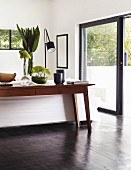 Various vases of leaves and flowers on table behind sofa in lounge area with sliding doors leading to terrace