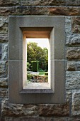 Window opening in stone wall with view of garden