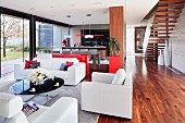 White leather sofa set around coffee table with black stone top in lounge area in open-plan interior with parquet floor; staircase in background