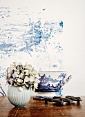 Hortensien in weisser Kugel Vase und weiss blau bemalte Schüssel, (Toile-de-Jouy), im Hintergrund Pflanzenstrukturen in Blau auf weisser Wand