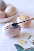 Decorating eggs using decoupage - glueing bird and butterfly motifs to eggs