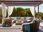 Roofed lounge area with outdoor furniture on wooden terrace in summer sunshine