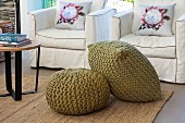 Olive-green pouffes in front of armchairs with washable loose covers and scatter cushions with floral motifs