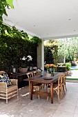 Seating area with bentwood chairs on roofed, paved terrace and sunny garden in background