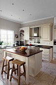 Pale country-house-style kitchen with free-standing counter and rustic bar stools